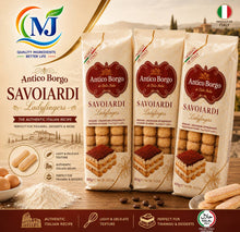 Three stand-up pouches of Antico Borgo Savoiardi Ladyfingers cookies are displayed on a wooden surface with cookies, flour, and coffee beans. The background shows a warm, blurred Italian landscape.